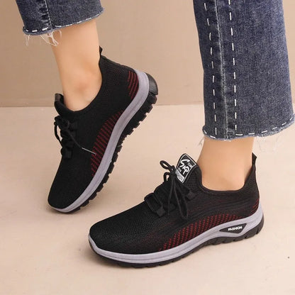 Women's low-top sneakers in black with a cross strap detail on the artificial PU and mesh upper.