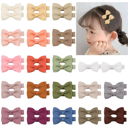 Assortment of pastel-coloured baby hair clips and bows arranged on a white background.