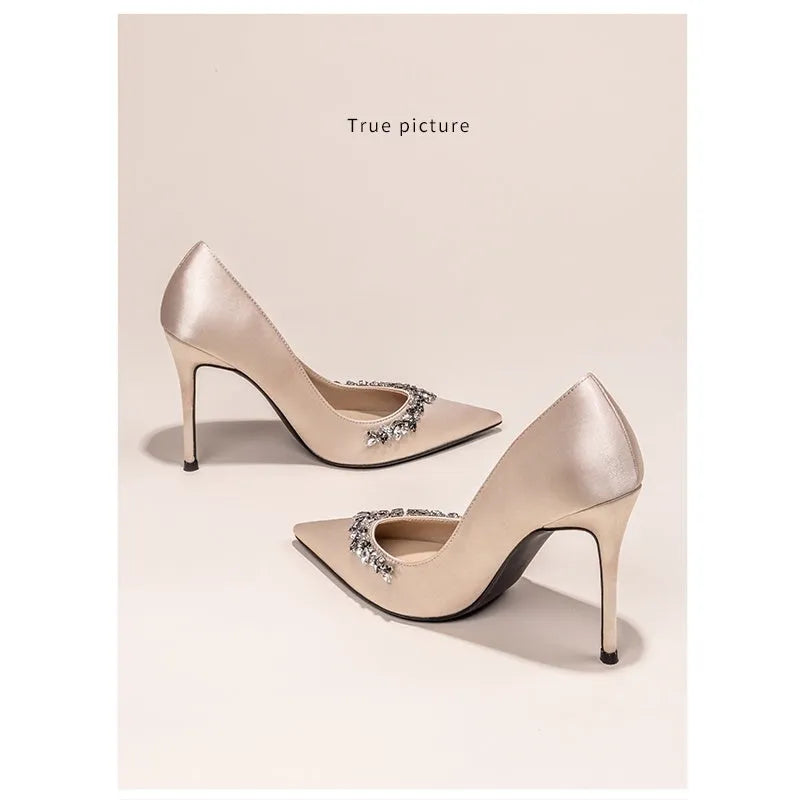 Women's stiletto high heels with pointed toe and French style rhinestone decoration, featuring a satin upper, sheepskin lining and insole, rubber sole, and available in black, skin, and white colours with heel heights of 6cm, 8cm, and 10cm.