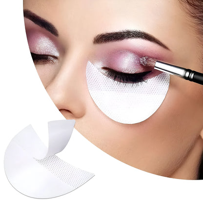 Pack of disposable half-moon shaped under-eye makeup shields on a pink background.