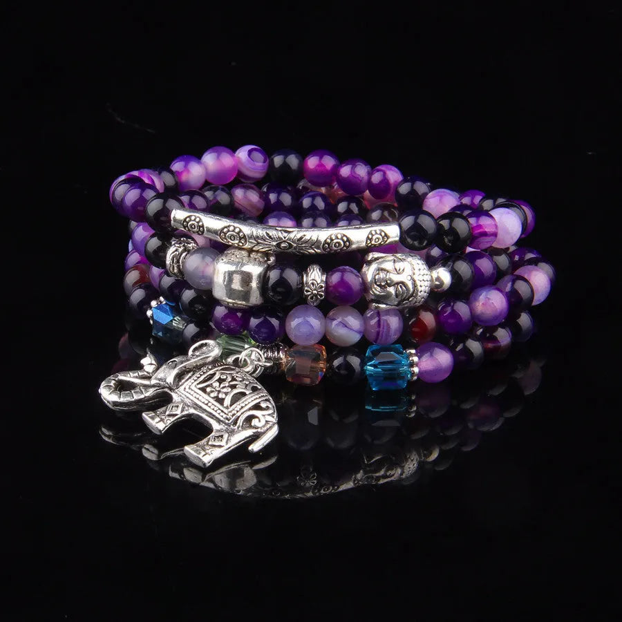 Multi-layer agate amulet bracelet with 6mm beads in blue elephant pattern on a wrist.