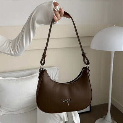 Women's silver dumpling-shaped PU crossbody bag showing front sandwich pocket and single shoulder strap.