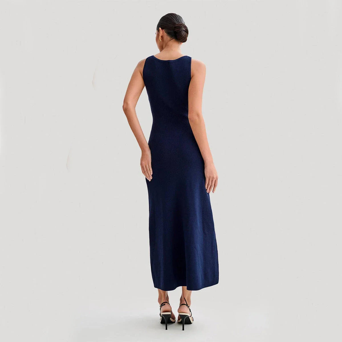 Elegant sleeveless knit dress in various colors, including almond and blue, with a slim, figure-flattering silhouette and round neckline