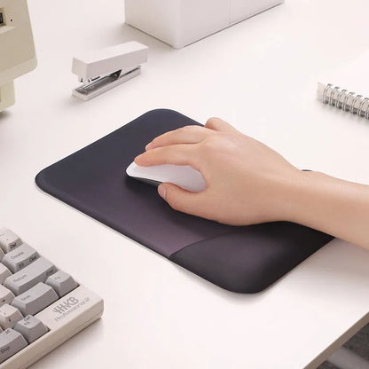 Square cloth mouse pad with grey silicone gel wrist rest and hand pillow on a wooden desk.