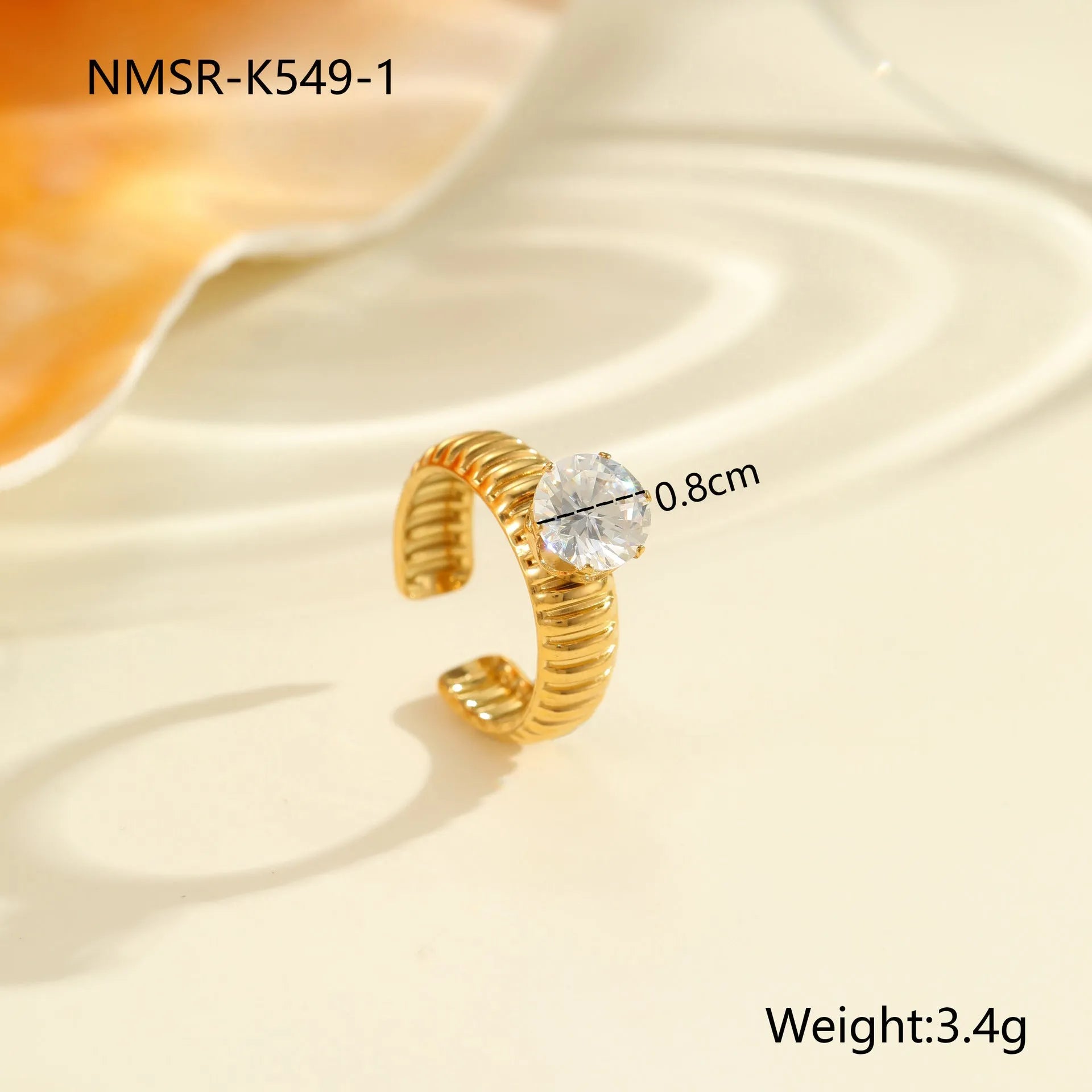Gold electroplated stainless steel open mouth ring with geometric shapes and zircon inlay on a heart drop.