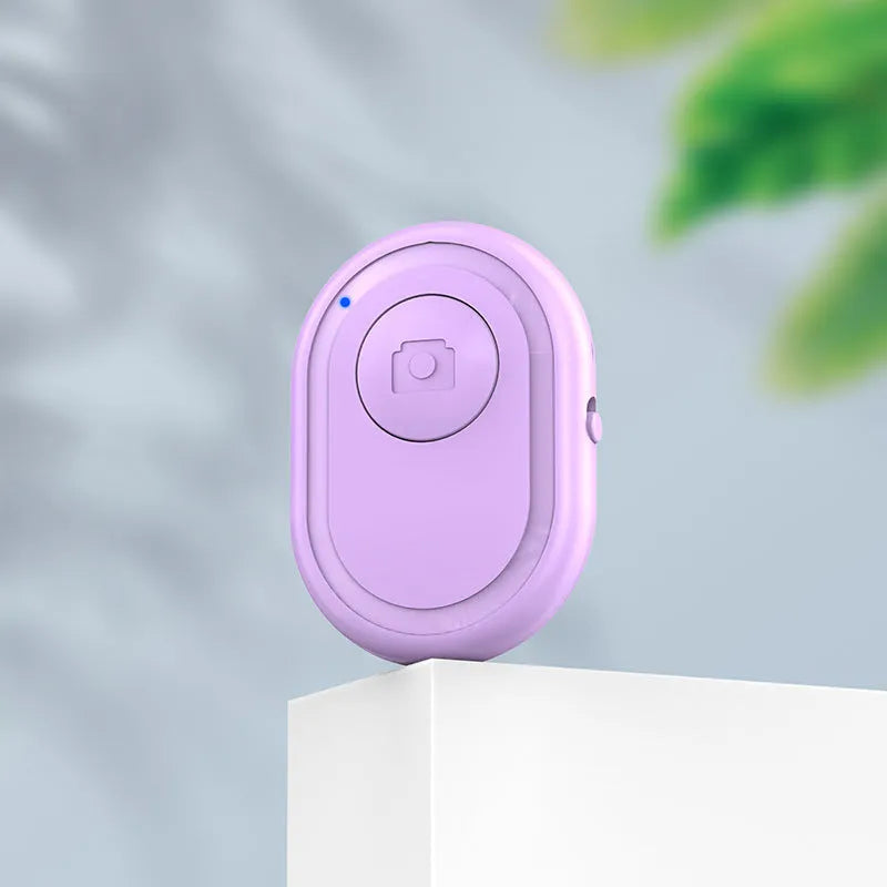 Small black wireless Bluetooth remote control for smartphone camera with self-timer function.