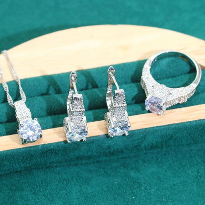 Four-piece bridal jewellery set with zircon pendants on a water wave chain, showing necklace, bracelet, earrings and ring.