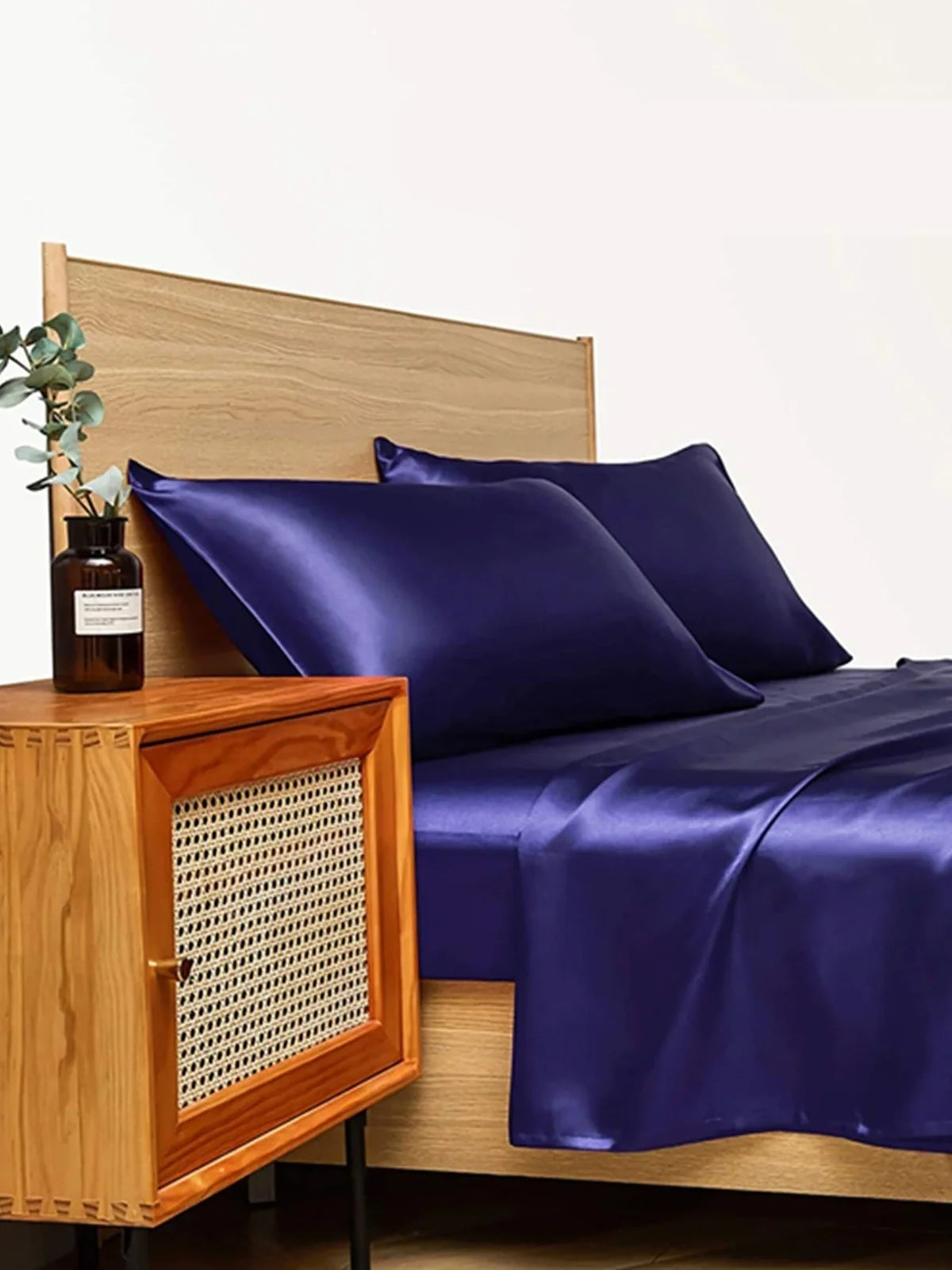 Navy blue floral pattern silk bedding set with quilt cover, fitted sheet, and two pillowcases on bed