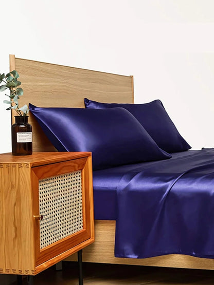 Navy blue floral pattern silk bedding set with quilt cover, fitted sheet, and two pillowcases on bed