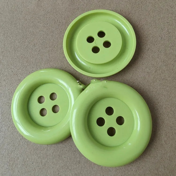 Assorted oversized round plastic buttons in various colours showing four-hole sew-through design.