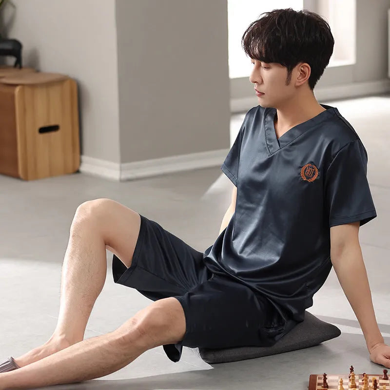 Man wearing a loose fit light blue ice silk short-sleeve pajama shirt and matching shorts.