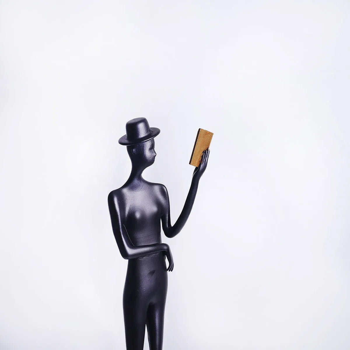 Black cast aluminium desktop sculpture of reading woman measuring 12x12x51cm with modern simplicity design