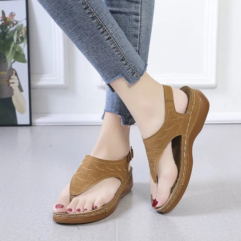 Women's wedge heel flip flop sandals in black with adjustable back strap on a light background