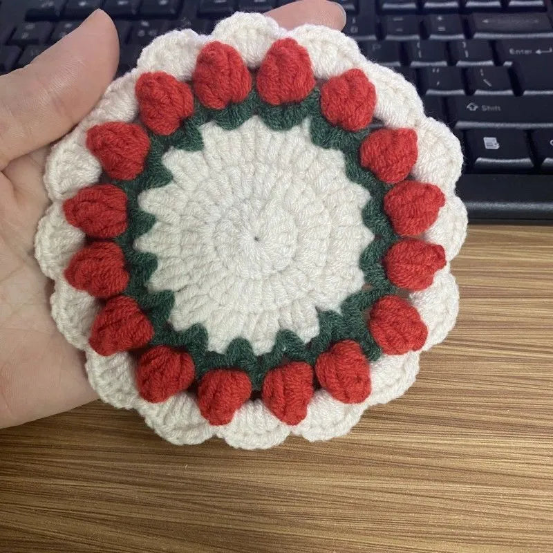Handmade woven flower coaster in cotton and linen on a wooden table.