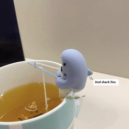 Shark-shaped tea infuser hanging on cup edge, made from food-grade silicone