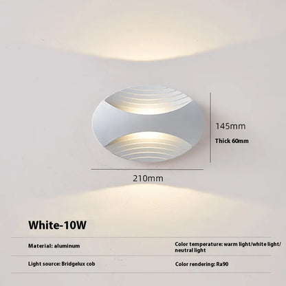 Modern aluminium wall lamp in black finish mounted beside a bed, emitting warm LED light.