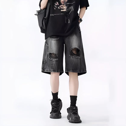 Man wearing loose fit black ripped denim shorts with distressed detailing and a washed vintage finish.