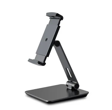 Silver foldable aluminium phone and tablet holder on a wooden desk, showing 360-degree rotation and silicone pads.