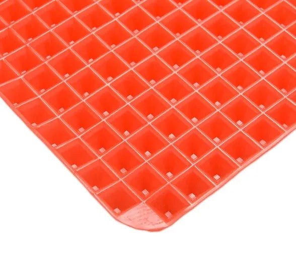 Red silicone pyramid grid cooking mat on a kitchen counter
