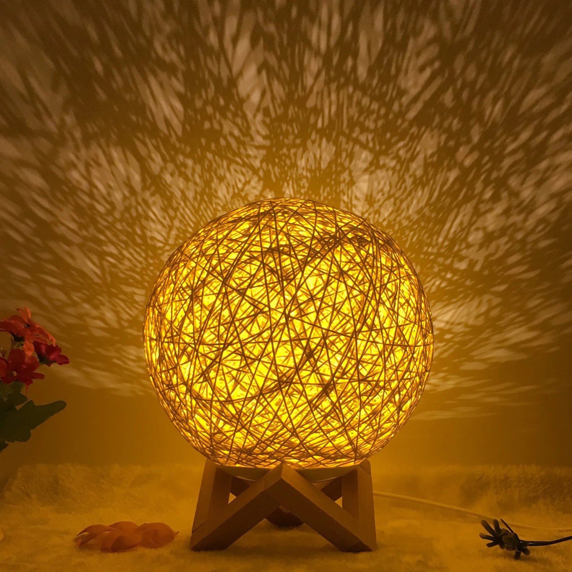 Spherical hand-knitted rattan table lamp with remote control on a wooden desk