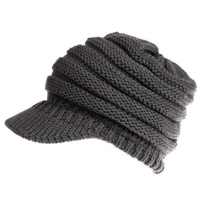 Woman wearing a light grey knitted ponytail beanie with her ponytail pulled through the hole in the back.