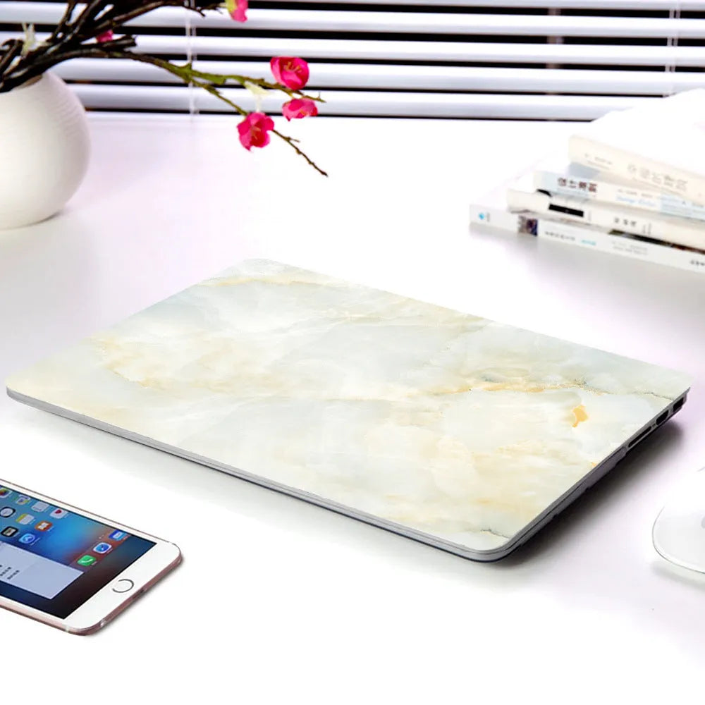 Plastic MacBook protective case in a marble pattern colour, shown next to a compatible Apple laptop.