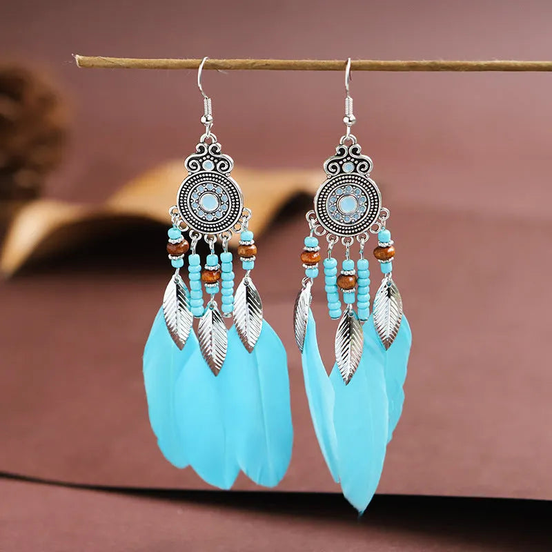 Bohemian feather leaf pattern alloy earrings in round drop shape on a colour selection background.