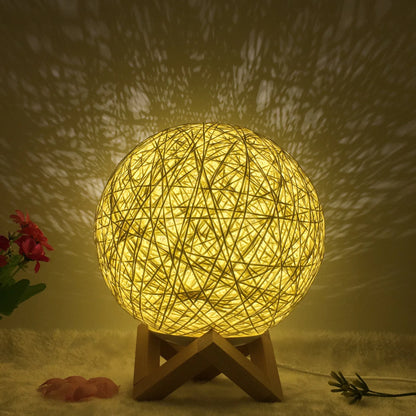 Spherical hand-knitted rattan table lamp with remote control on a wooden desk
