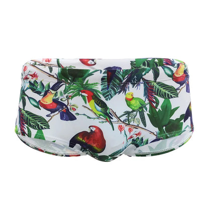 Men's blue swimming trunks with a detailed floral and bird print pattern, shown in a brief style.