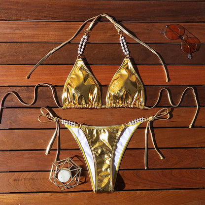 Gold women's halter neck bikini with lace-up front and pearl chain decoration on a solid background.