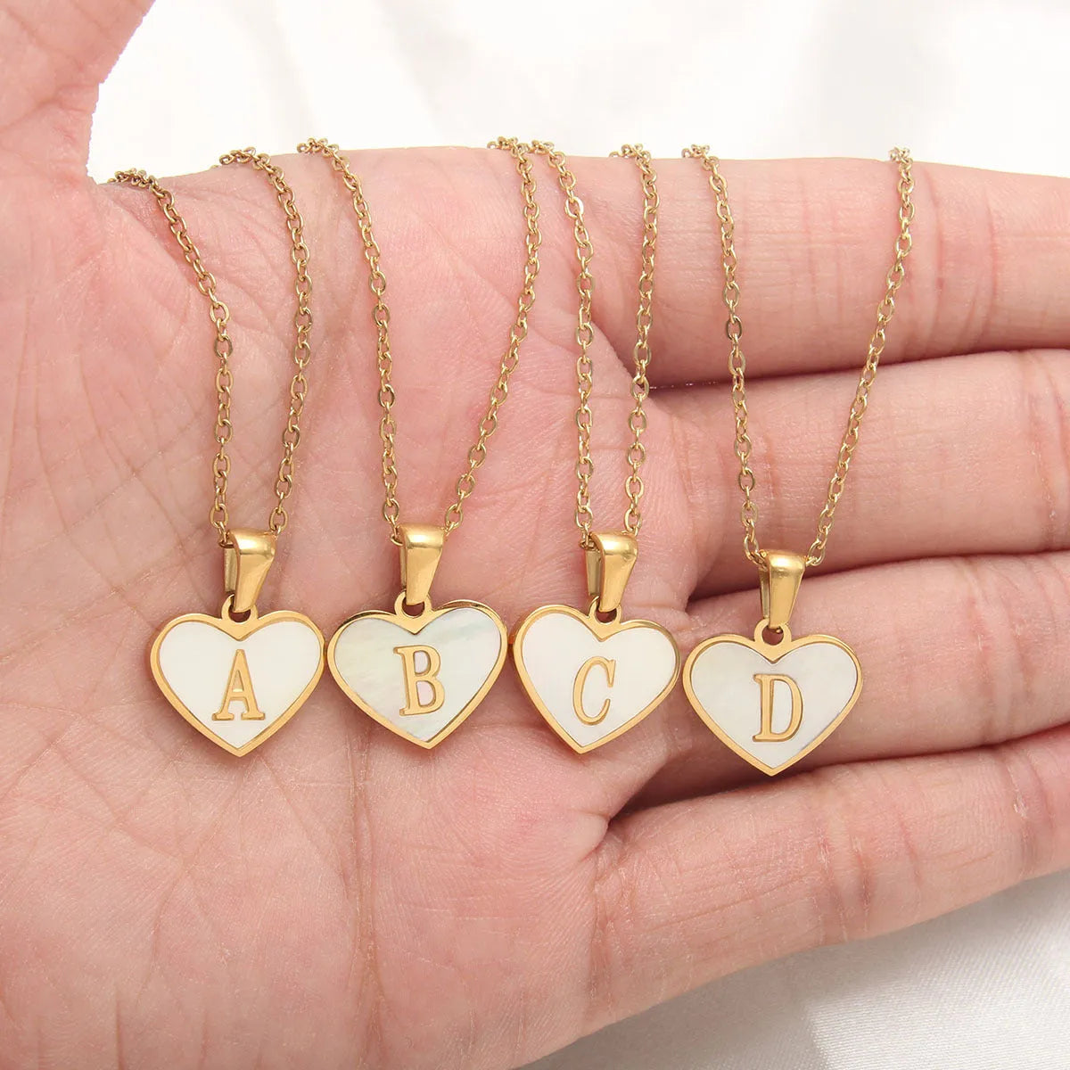 Gold-plated clavicle necklace with a white shell heart pendant, personalised with a letter from A to Z.