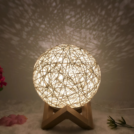 Spherical hand-knitted rattan table lamp with remote control on a wooden desk