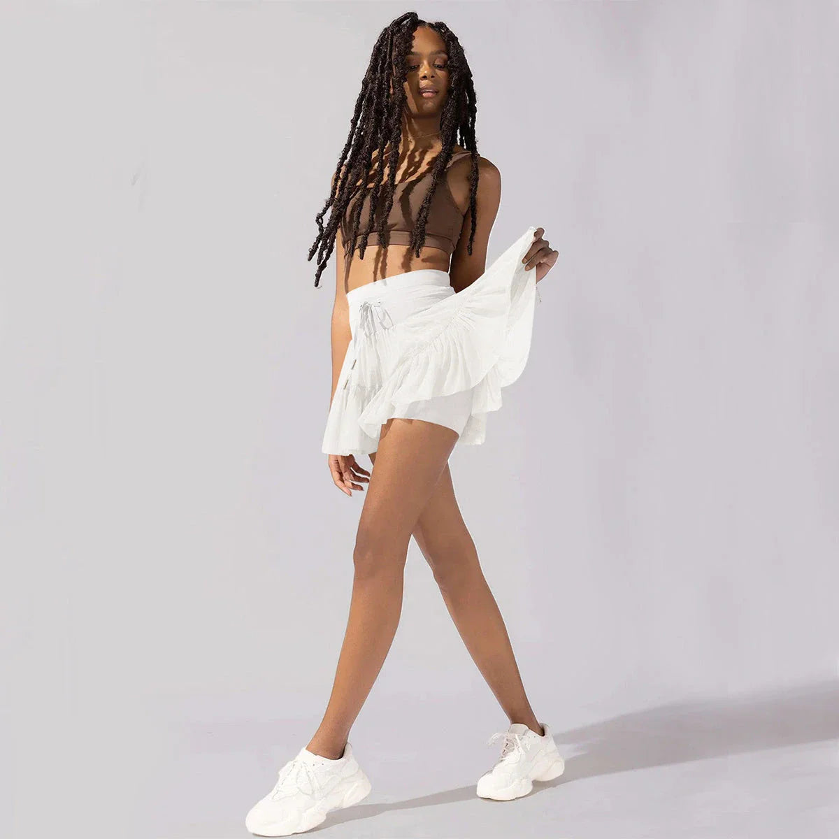 Stylish high-waist pleated mini skirt with lace-up design and built-in anti-exposure safety shorts, available in a variety of vibrant colors.