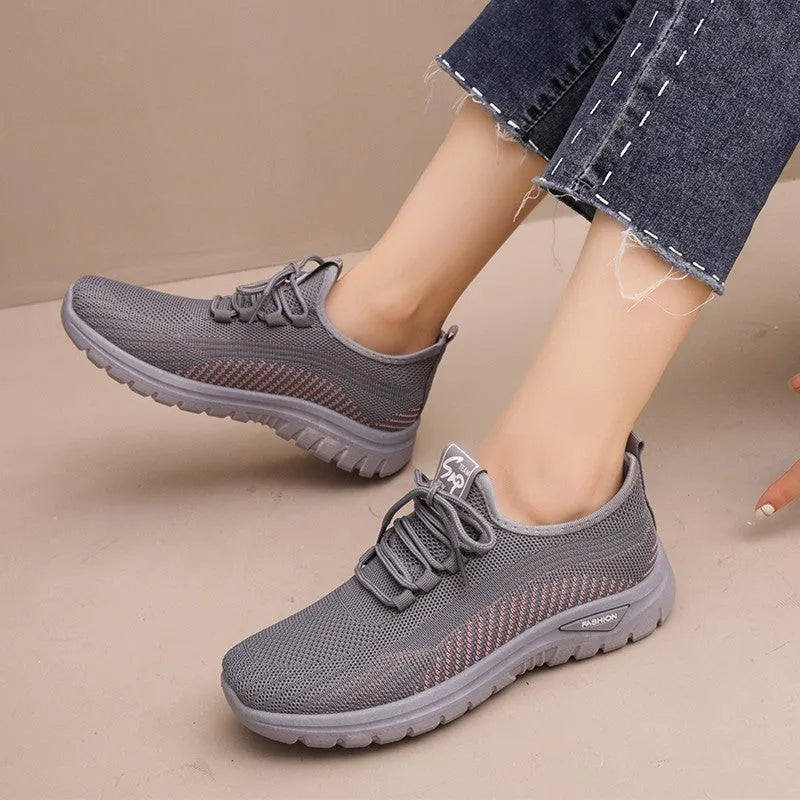 Women's low-top sneakers in black with a cross strap detail on the artificial PU and mesh upper.
