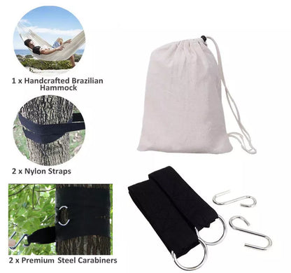 Cotton camping hammock with adjustable straps hanging between two trees in a forest