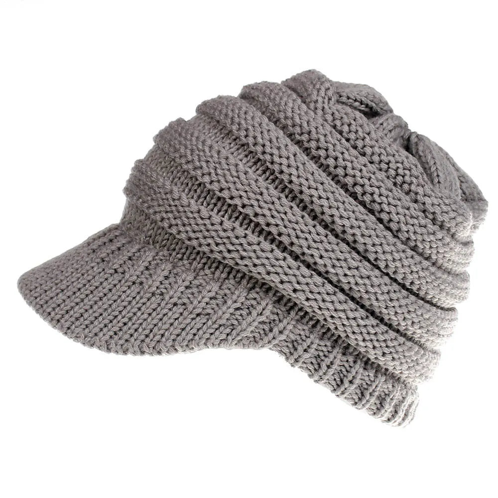 Woman wearing a light grey knitted ponytail beanie with her ponytail pulled through the hole in the back.
