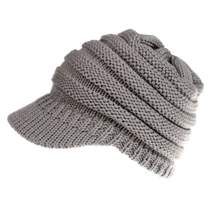 Woman wearing a light grey knitted ponytail beanie with her ponytail pulled through the hole in the back.