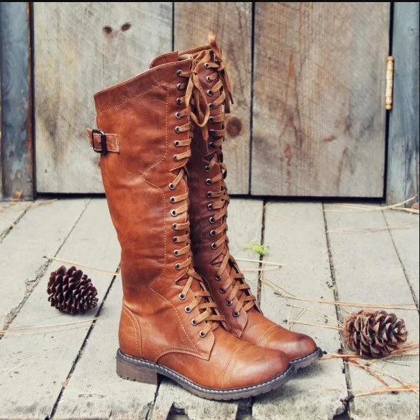 Women's black knight ankle boots with a cross strap fastening detail.