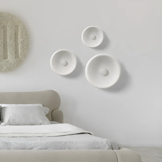 Minimalist Japanese-style wall lamp with a white resin shade in three size options on a plain wall.