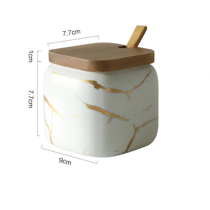Three-piece Nordic Gold Marble Jar Set in white ceramic with wooden tray and bamboo spoons on kitchen counter