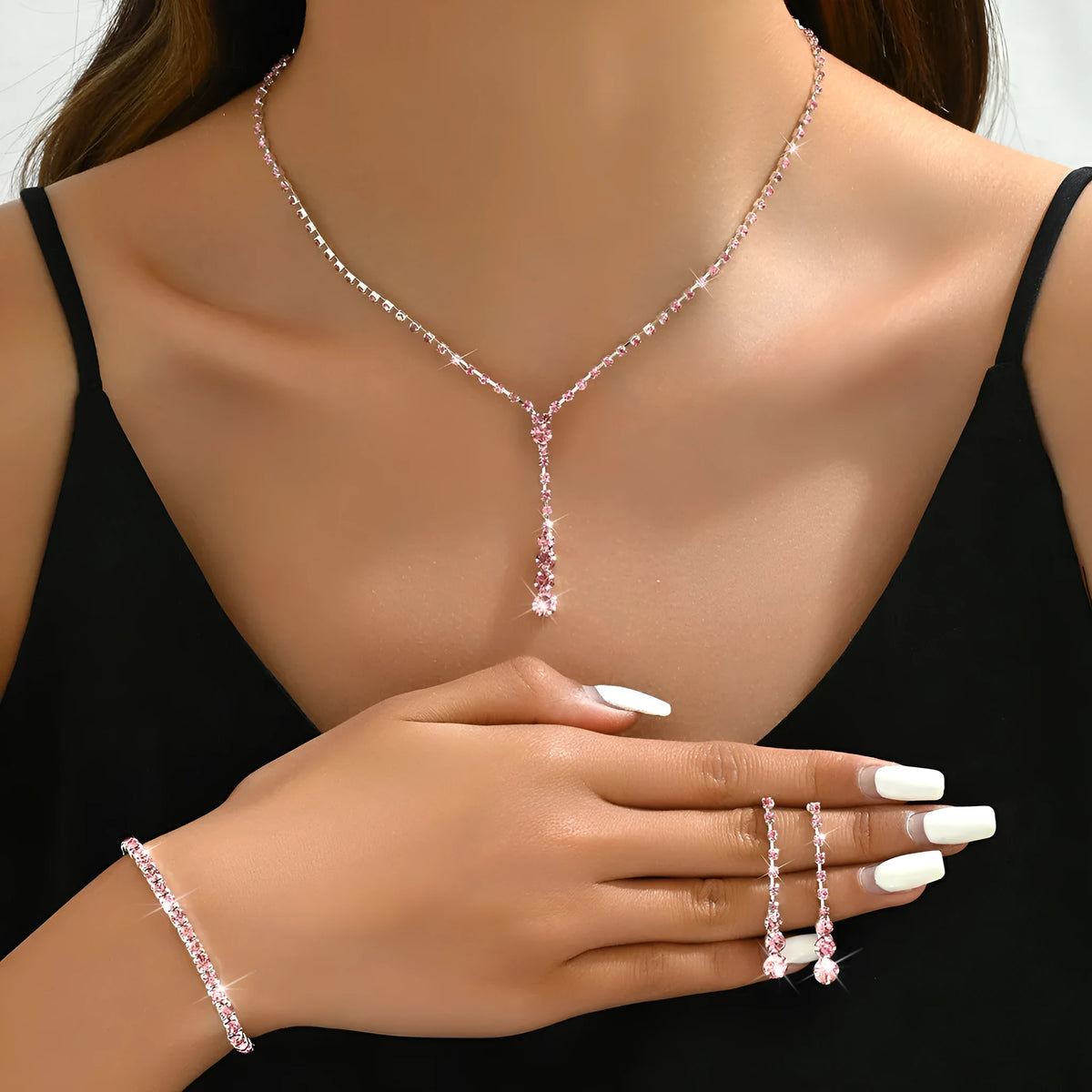 Women's silver pink rhinestone heart tassel earrings, necklace, and bracelet jewellery set on a white background.