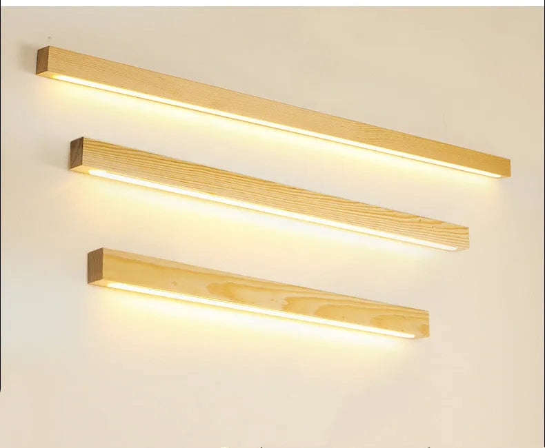 Walnut-coloured minimalist wooden strip wall lamp with integrated LEDs, mounted on a plain wall.