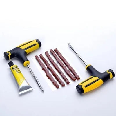 Black and yellow vacuum tyre repair tool kit with rubber strips, glue, and tools on plastic packaging.