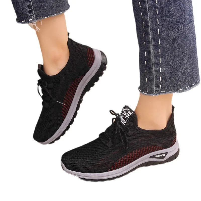 Women's low-top sneakers in black with a cross strap detail on the artificial PU and mesh upper.