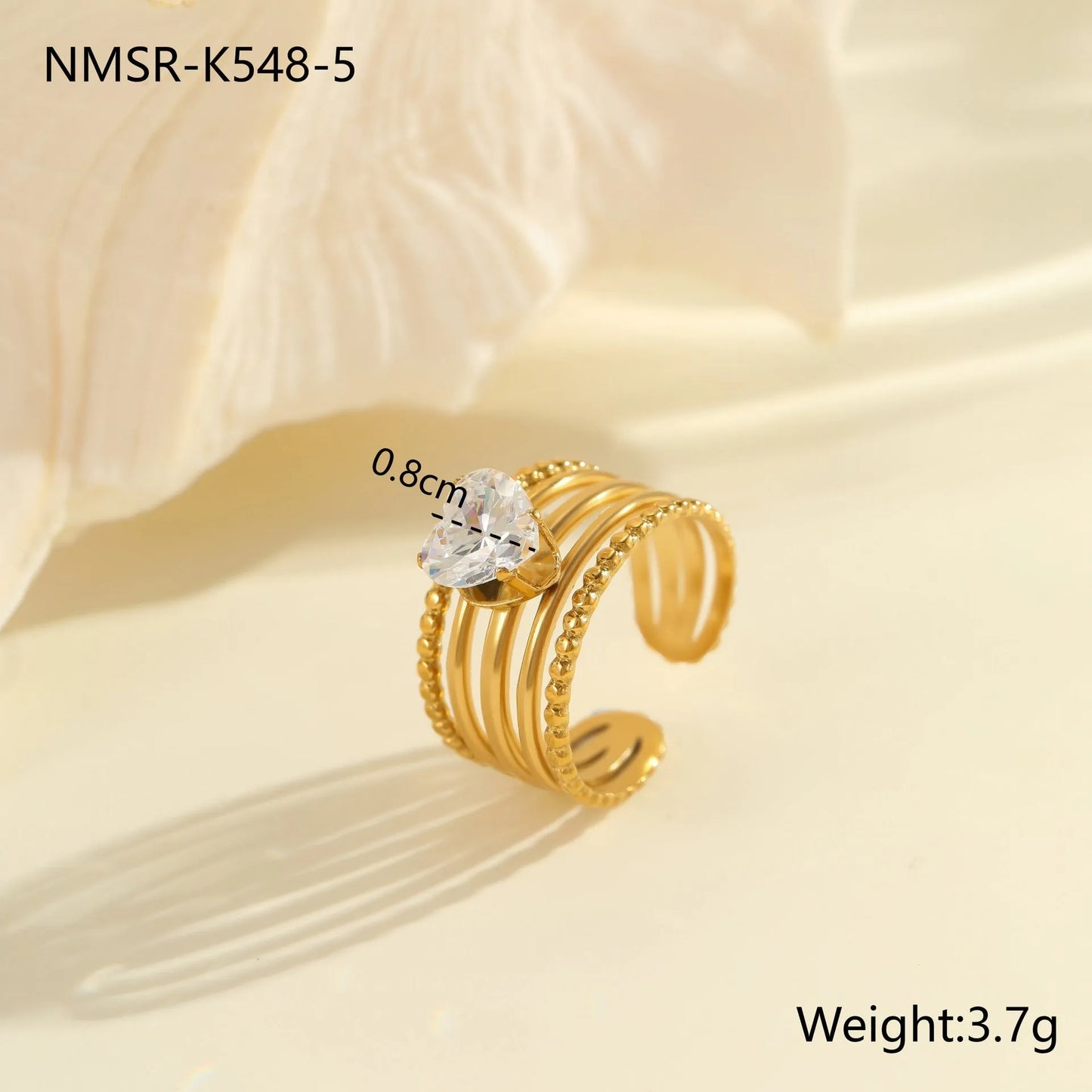 Gold electroplated stainless steel open mouth ring with geometric shapes and zircon inlay on a heart drop.