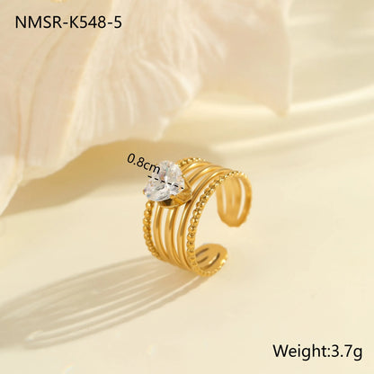 Gold electroplated stainless steel open mouth ring with geometric shapes and zircon inlay on a heart drop.