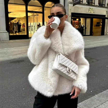 Women's white artificial fur coat with large lapel, long sleeves, and deep pockets shown in street fashion setting