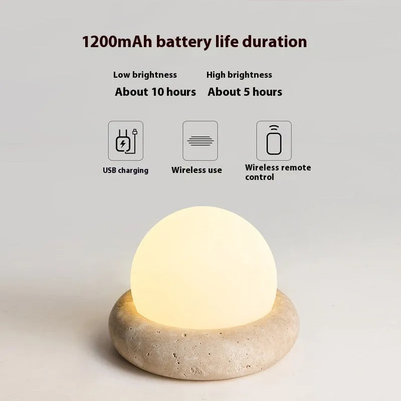 Modern white bedside night lamp with remote control on a wooden table.