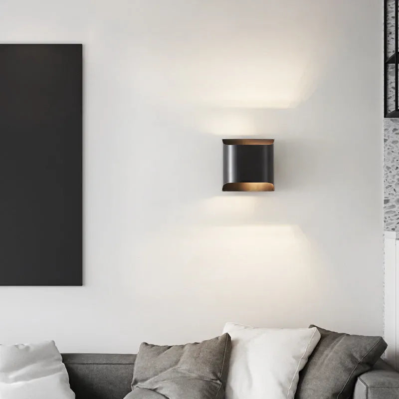 Minimalist copper wall lamp in black gold finish mounted beside bed