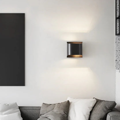 Minimalist copper wall lamp in black gold finish mounted beside bed